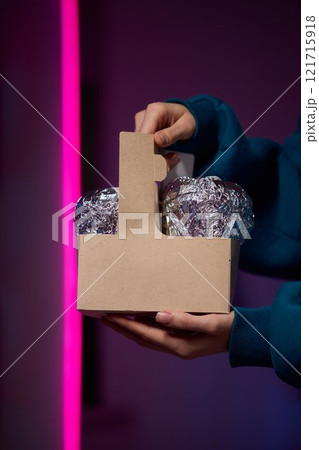 Hands holding a stylish brown paper basket that features a shiny metallic foil lid design Hands holding a stylish brown paper basket that features a shiny metallic foil lid design 121715918