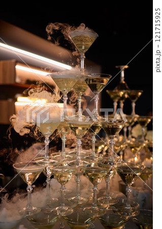 An elegant and stunning Champagne Tower adorned with a mysterious and enchanting smoke effect An elegant and stunning Champagne Tower adorned with a mysterious and enchanting smoke effect 121715925