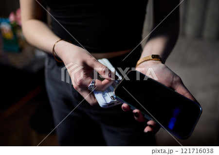 A User is Holding a Smartphone and Power Bank in a Modern and Stylish Setting Today A User is Holding a Smartphone and Power Bank in a Modern and Stylish Setting Today 121716038