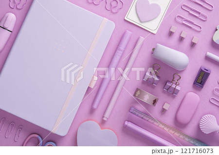 Stationery background with pastel purple supplies, notepad, paper clips, scissors, post-it notes, felt tip pens, eraser, stapler, ruler, pins 121716073