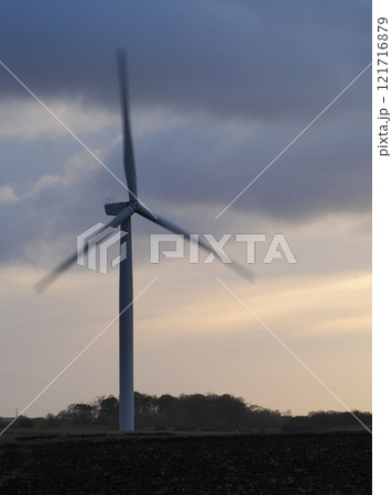 A wind turbine spinning on a windy day against a stormy and overcast evening sky A wind turbine spinning on a windy day against a stormy and overcast evening sky 121716879