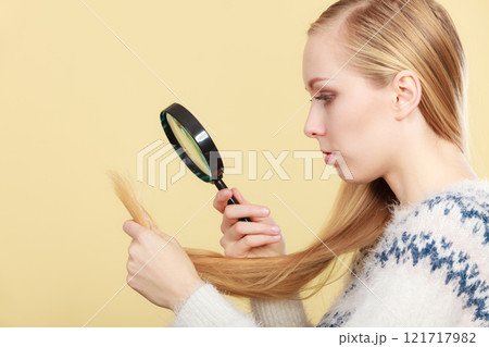 Sad woman looking at damaged hair ends. 121717982