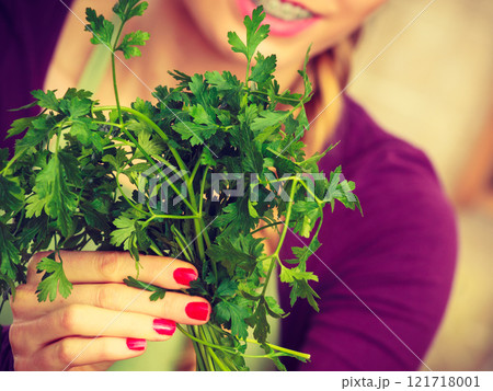 Woman holding green herb, parsley Woman holding green herb, parsley 121718001