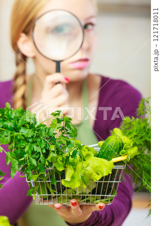 Woman looking magnifier at vegetables Woman looking magnifier at vegetables 121718011