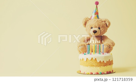 A cute teddy bear wearing a party hat, sitting next to a birthday cake with candles. 121718359