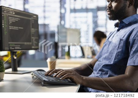 Computer scientist in office fixing applications issues, dealing with databases and server configuration. African american IT expert optimizing company software for improved performance 121718492
