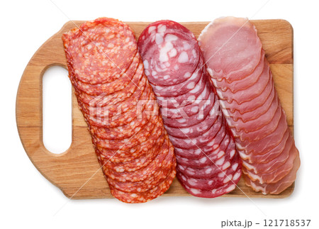 Thin sliced sausage on a wooden board on a white background. Top view Thin sliced sausage on a wooden board on a white background. Top view 121718537