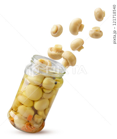 Marinated champignon mushrooms fly out of a glass jar on a white background. Isolated Marinated champignon mushrooms fly out of a glass jar on a white background. Isolated 121718540