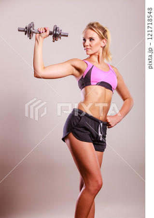 Fit woman lifting dumbbells weights 121718548