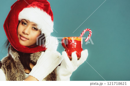 Winter girl santa helper hat holds red mug Winter girl santa helper hat holds red mug 121718621