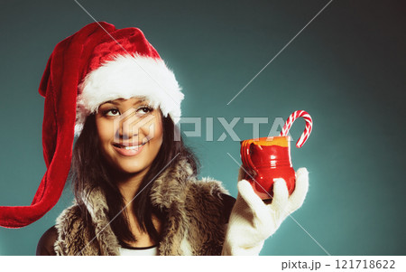 Winter girl santa helper hat holds red mug Winter girl santa helper hat holds red mug 121718622