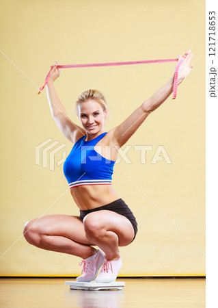 Joyful girl standing on bathroom scales 121718653