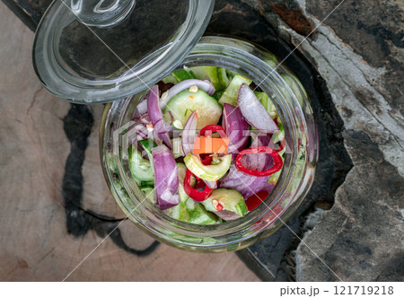 Top view of Homemade thai cucumber slices, chili slices and shallots relish slices and vinegar in a glass jar. Top view of Homemade thai cucumber slices, chili slices and shallots relish slices and vinegar in a glass jar. 121719218
