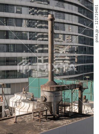 Boiler soot separator chimney on roof of building with modern buildings in the background. Boiler soot separator chimney on roof of building with modern buildings in the background. 121719401