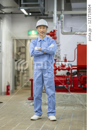 カメラ目線で腕組みをした作業服姿のシニア男性　ビルメンテナンススタッフ　イメージ　 121719804