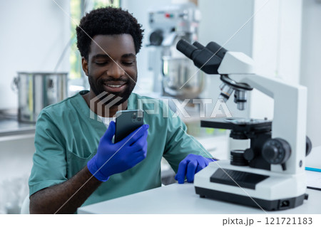 Medical man working in lab using smartphone and microscope for analysis and research 121721183