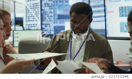 Enterprise manager works with his staff on creating a business strategy and setting goals, studying market dynamics and sales numbers. Corporation team attends a development meeting. Camera A. 121721346