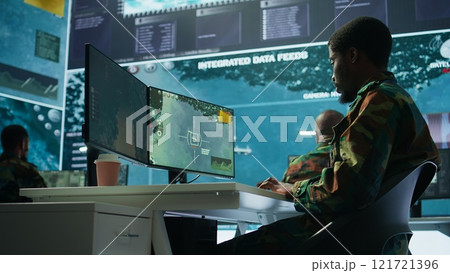 Military personnel in a control center working on data processing, integrating real time surveillance and security protocols essential for national defense and strategic operations. Camera B. 121721396