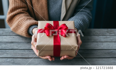 A close-up of hands giving a beautifully wrapped gift to another person. The scene conveys warmth, care, and symbolizes gratitude. A close-up of hands giving a beautifully wrapped gift to another person. The scene conveys warmth, care, and symbolizes gratitude. 121721888