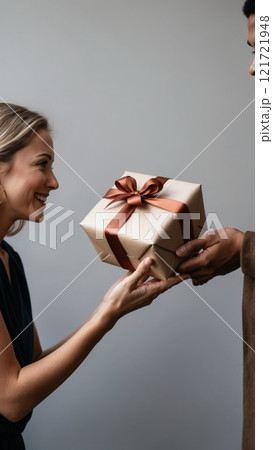 A close-up of hands giving a beautifully wrapped gift to another person. The scene conveys warmth, care, and symbolizes gratitude. 121721948