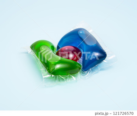 Liquid powder in gel capsule for washing multicolor on blue background Liquid powder in gel capsule for washing multicolor on blue background 121726570
