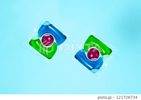 Liquid powder in gel capsule for washing multicolor on blue background Liquid powder in gel capsule for washing multicolor on blue background 121726734