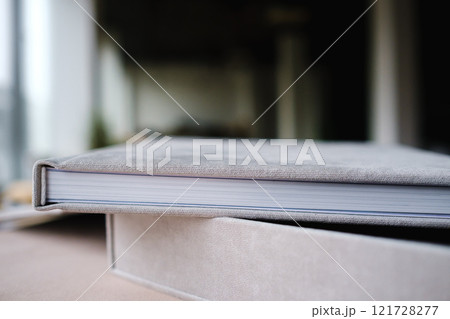 A photo book in a grey cloth cover lies on the box. the concept of creating books and albums from photographs. professional photographer and printing services 121728277