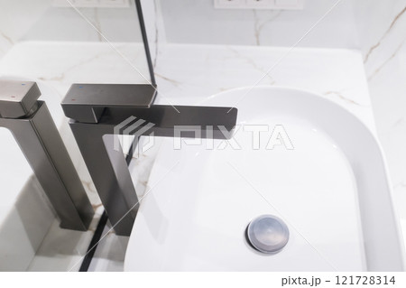 Stylish deluxe water faucet and white countertop sink in bathroom. Stylish bathroom 121728314