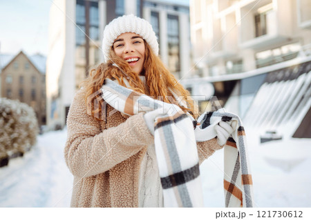 Smiling woman in a scarf and hat is having fun at street holiday fair, drinking hot drink. Smiling woman in a scarf and hat is having fun at street holiday fair, drinking hot drink. 121730612