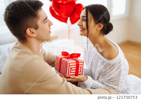 Young couple at home celebrating Valentine's Day. Exchange of gifts. Surprise and love concept. 121730753