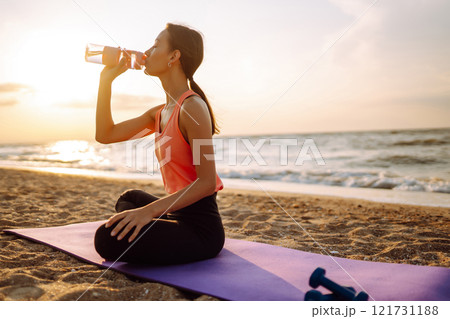 Modern young woman doing yoga on beach at sunrise. Concept of an active lifestyle, yoga or fitness. 121731188