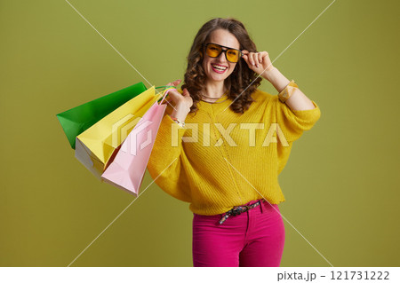 happy trendy female in sweater and sunglasses against green 121731222