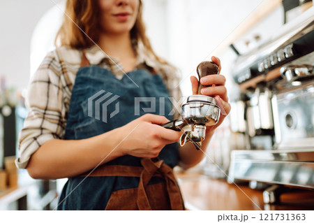 Woman bartender prepares a drink using a coffee machine in a cafe. Takeaway food. Woman bartender prepares a drink using a coffee machine in a cafe. Takeaway food. 121731363