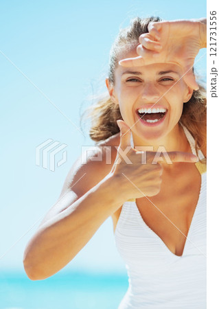 Smiling young woman on beach framing with hands Smiling young woman on beach framing with hands 121731556