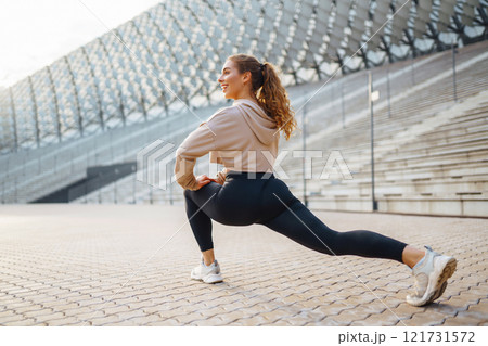 Young woman in sportswear is training outdoors. Sports concept, healthy body. 121731572