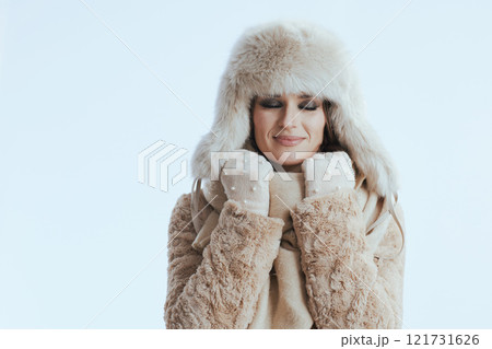 relaxed stylish woman in winter coat and fur hat on white 121731626