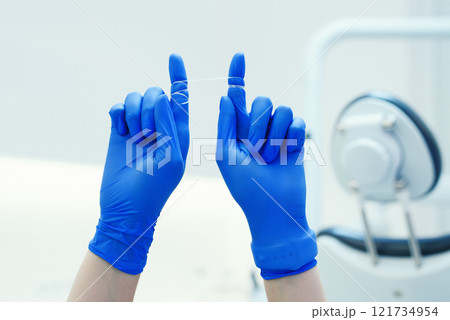 Selective focus on dental floss for dental care in the female hands of dental hygienist 121734954
