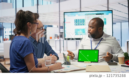 Financial advisor works with a green screen at table with his senior clients, presenting retirement plans and investment options to secure their pension and life savings. Insurance agency. Camera B. 121735288