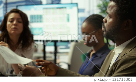 Important business investor studying development progress reports on tablet, examining big data visualization tools during a briefing meeting with executive board members. Management. Camera B. Important business investor studying development progress reports on tablet, examining big data visualization tools during a briefing meeting with executive board members. Management. Camera B. 121735303