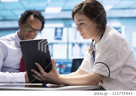 Healthcare provider presenting lab test results to a patient in cabinet, reviewing x ray and MRI scans to assist man on the road to recovery. Medical technology in diagnostics and care management. Healthcare provider presenting lab test results to a patient in cabinet, reviewing x ray and MRI scans to assist man on the road to recovery. Medical technology in diagnostics and care management. 121735443