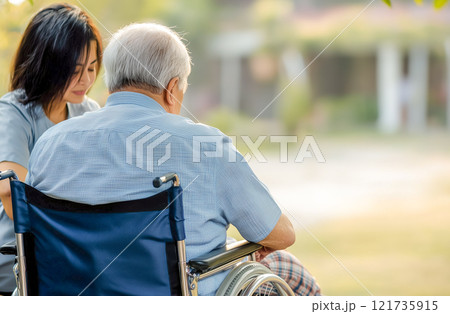 車椅子の老人に付き添う思いやりのある介護者 121735915