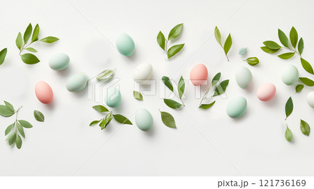 Charming arrangement of hand-painted pastel eggs and small bunny figurines scattered with fresh green leaves on a bright background for Easter 121736169