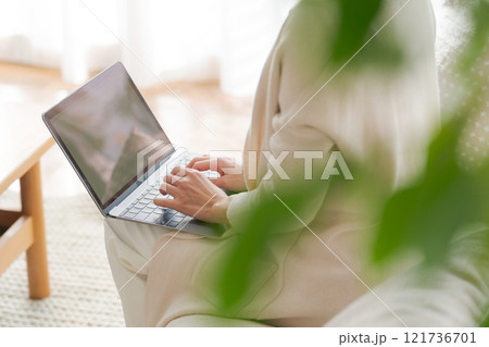 ソファでパソコン作業をする女性 121736701