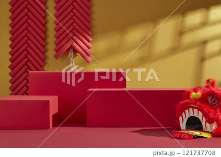 Three empty red platforms for product displays, decorated by a red lion dancing head, a paper fan, and strings of red firecrackers on a golden backdrop. Advertising photo with Chinese New Year theme. Three empty red platforms for product displays, decorated by a red lion dancing head, a paper fan, and strings of red firecrackers on a golden backdrop. Advertising photo with Chinese New Year theme. 121737708