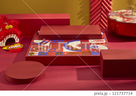 A high angle of product displays on some empty red platforms with firecrackers, a tray of pastries and jams, and a red lion dancing head against a golden background. A Chinese New Year theme. 121737714