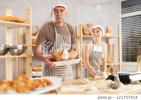 Male baker holding bread in basket and teenage girl kneading dough 121737814