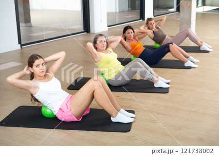Women practicing pilates with balls at group class in yoga studio 121738002