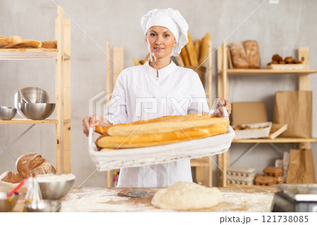 Woman baker holding baguettes Woman baker holding baguettes 121738085