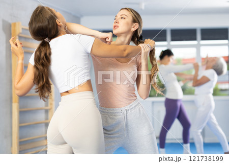 Woman practicing hand blocking with elbow strike to chin during sparring at self-defense training 121738199