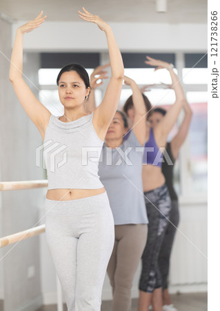 Woman practicing fifth ballet position with group of female amateurs Woman practicing fifth ballet position with group of female amateurs 121738266